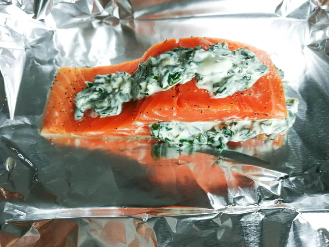 Filetes de salmón rellenos con espinacas y queso crema sobre papel aluminio antes de hornear