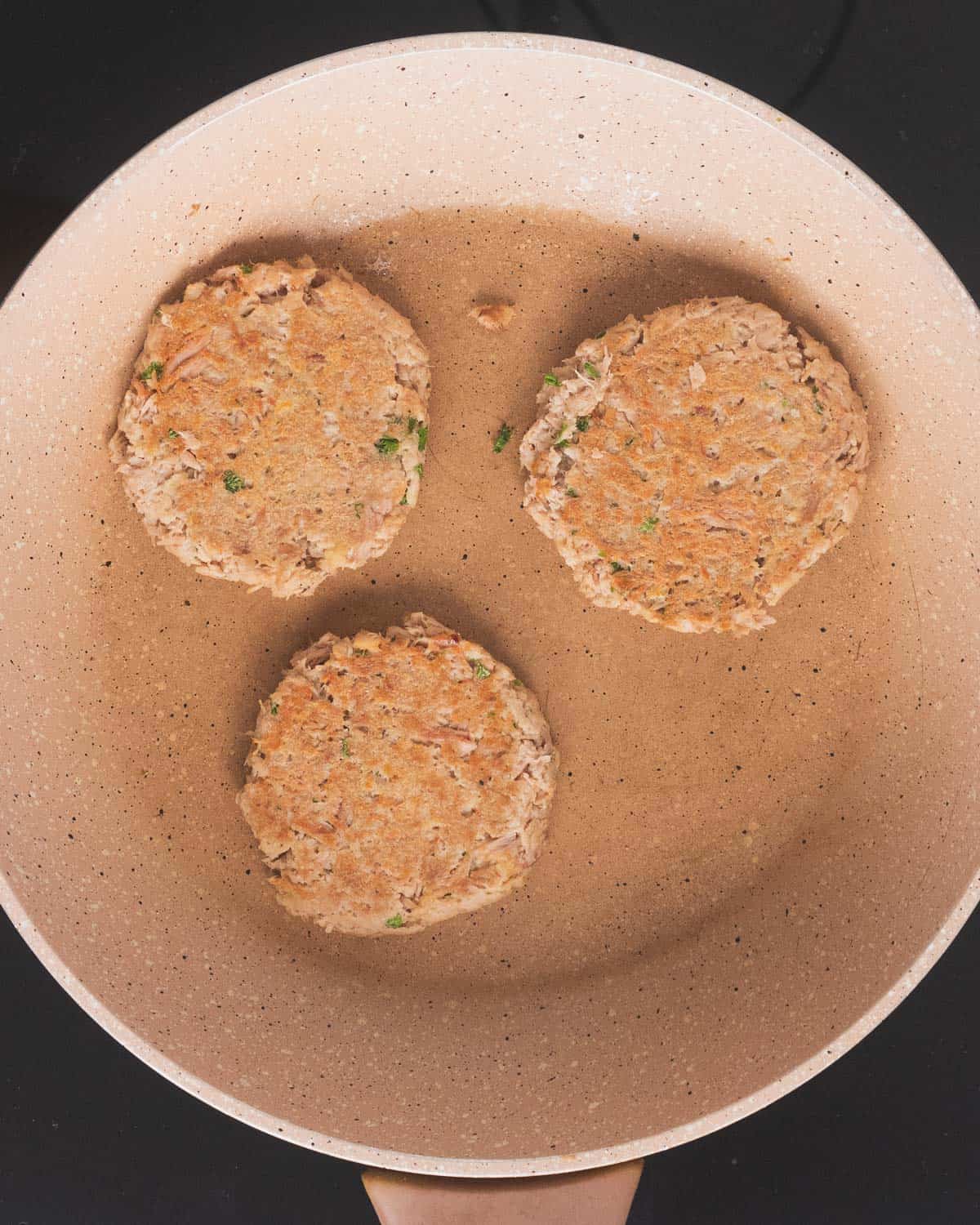 3 browned tuna patties in a skillet.