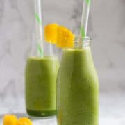 Two bottles with green smoothie and straws.
