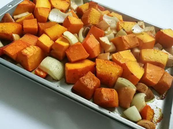 a baking pan with roasted vegetables (pumpkin, onions, apples, carrots).