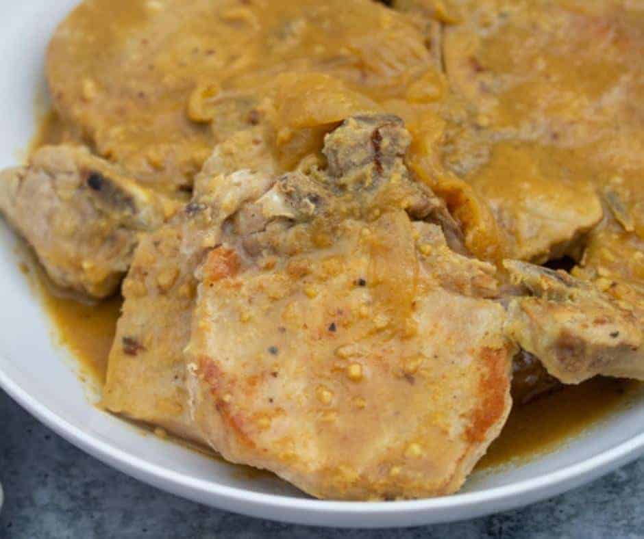 a plate with pork chops and maple dijon sauce.