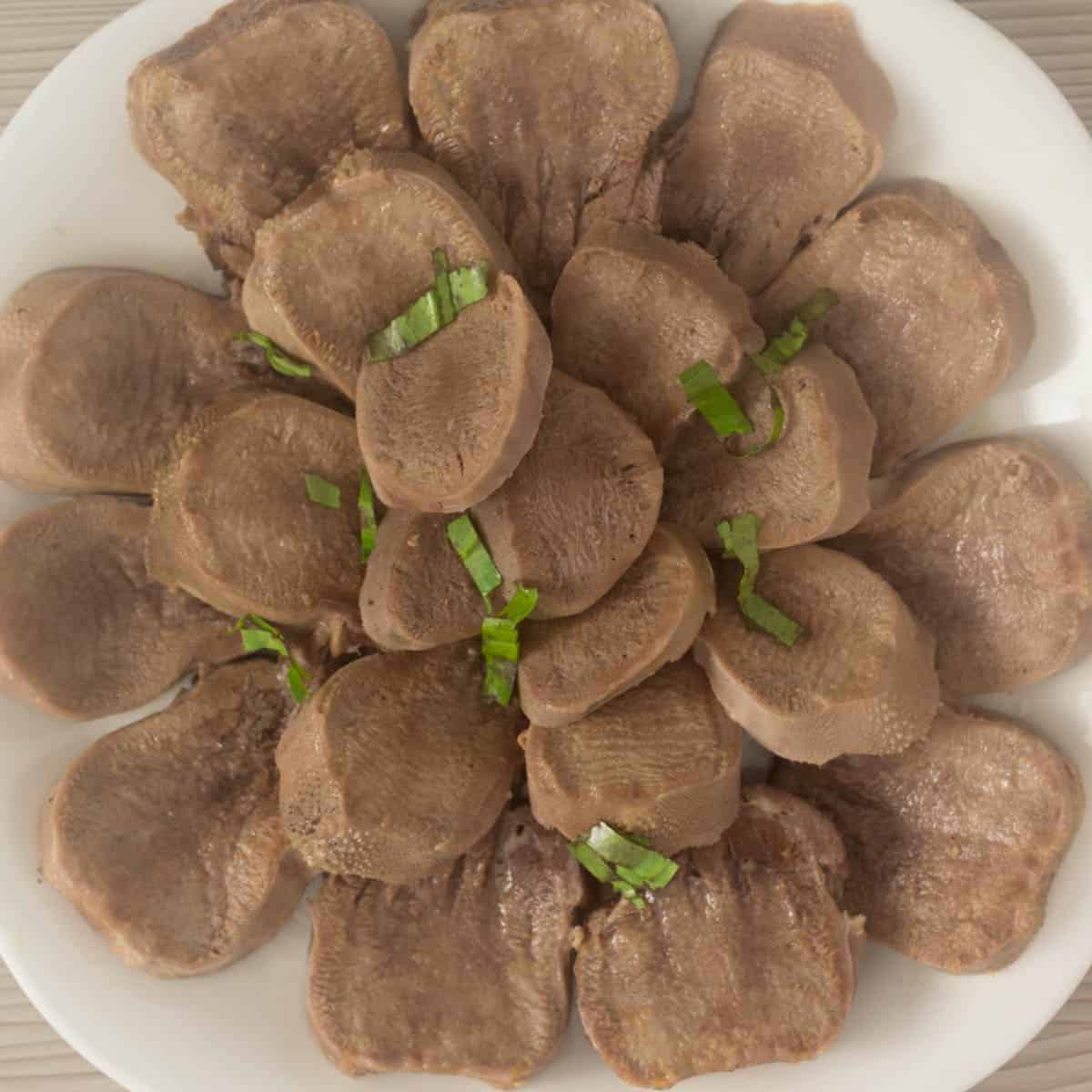 a plate with slices of cooked beef tongue.