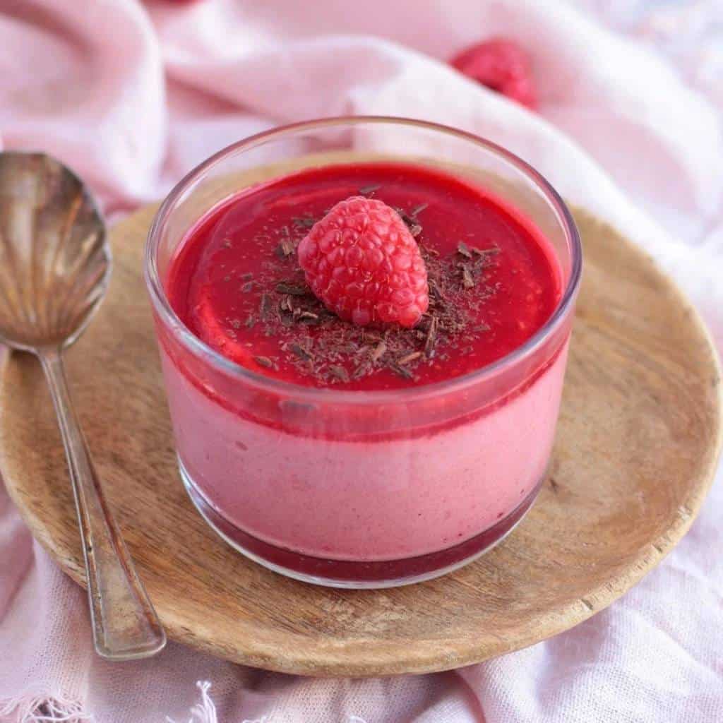 glass with raspberry mousse decorated with shaved chocolate and a raspberry