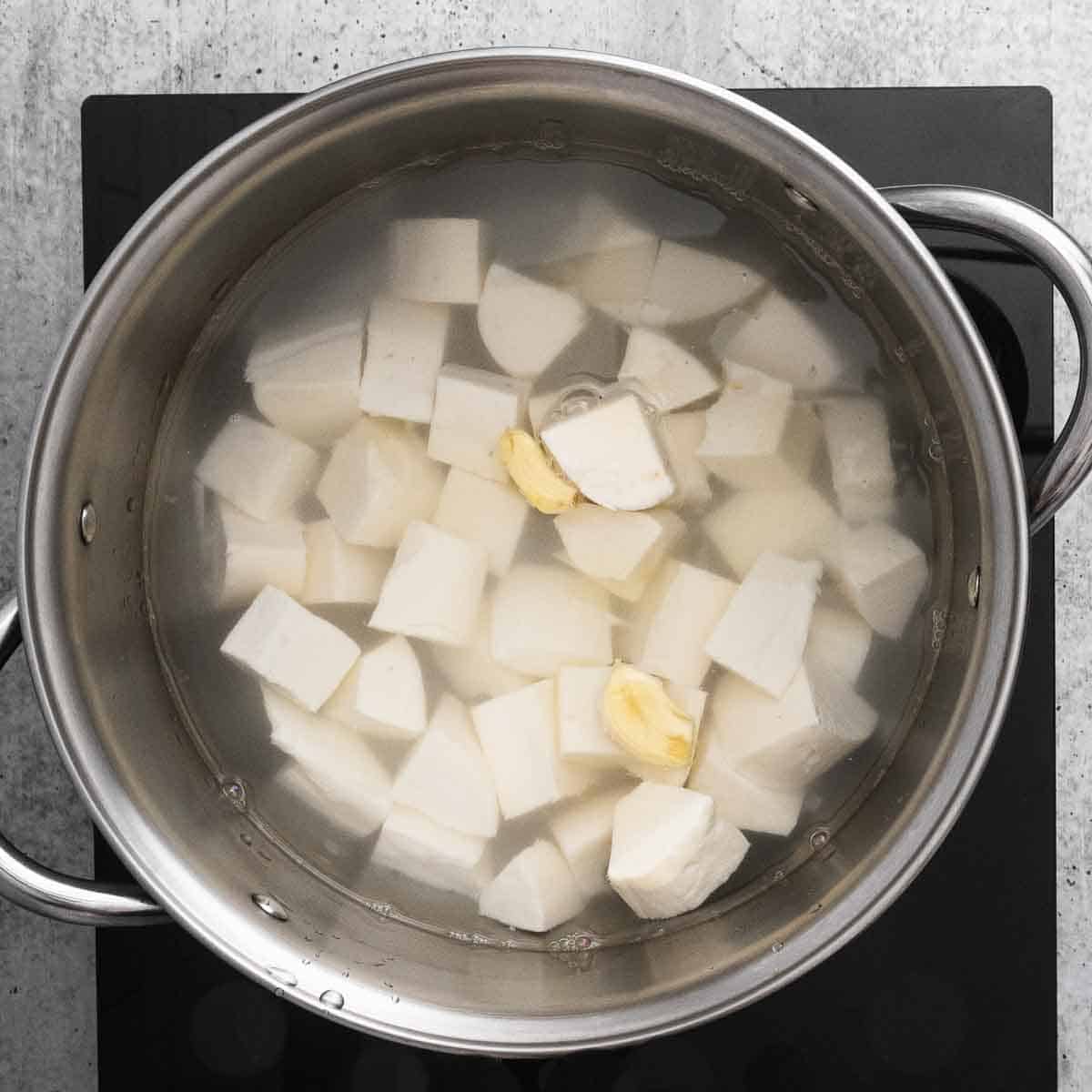 top view of the pot with yuca, garlic cloves and water