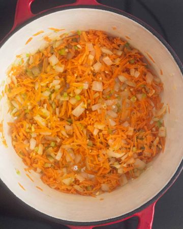 vista superior de una olla con cebolla, apio, ajo y zanahorias ralladas todo salteado