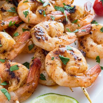 four chipotle lime shrimp skewers on a plate.