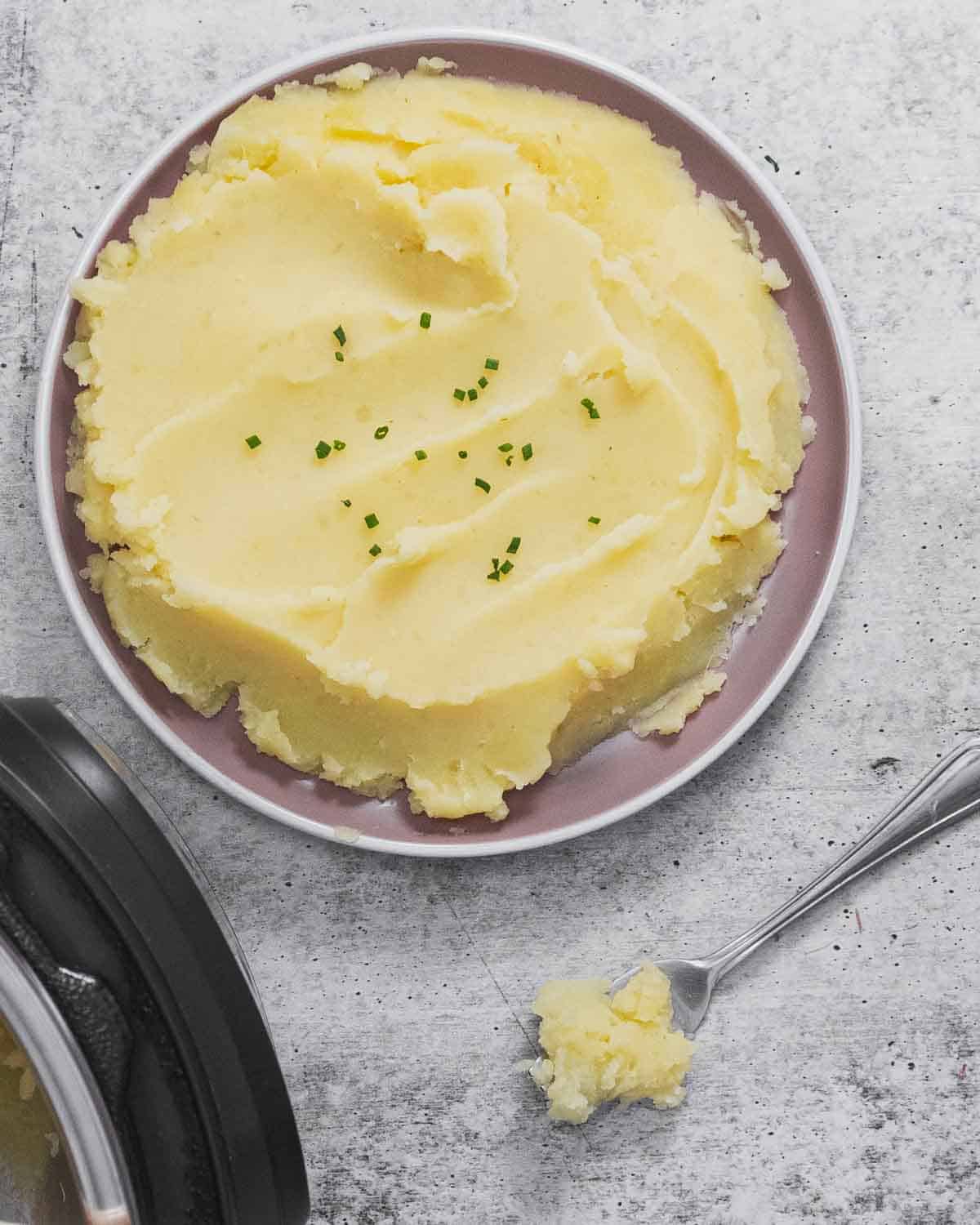 Garlic mashed potatoes served on a plate garnished with green onions.