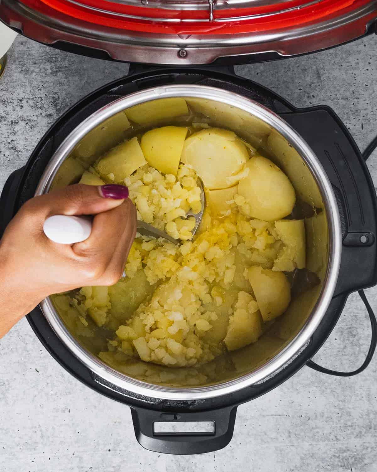 Mashing cooked russet potatoes inside an Instant Pot.
