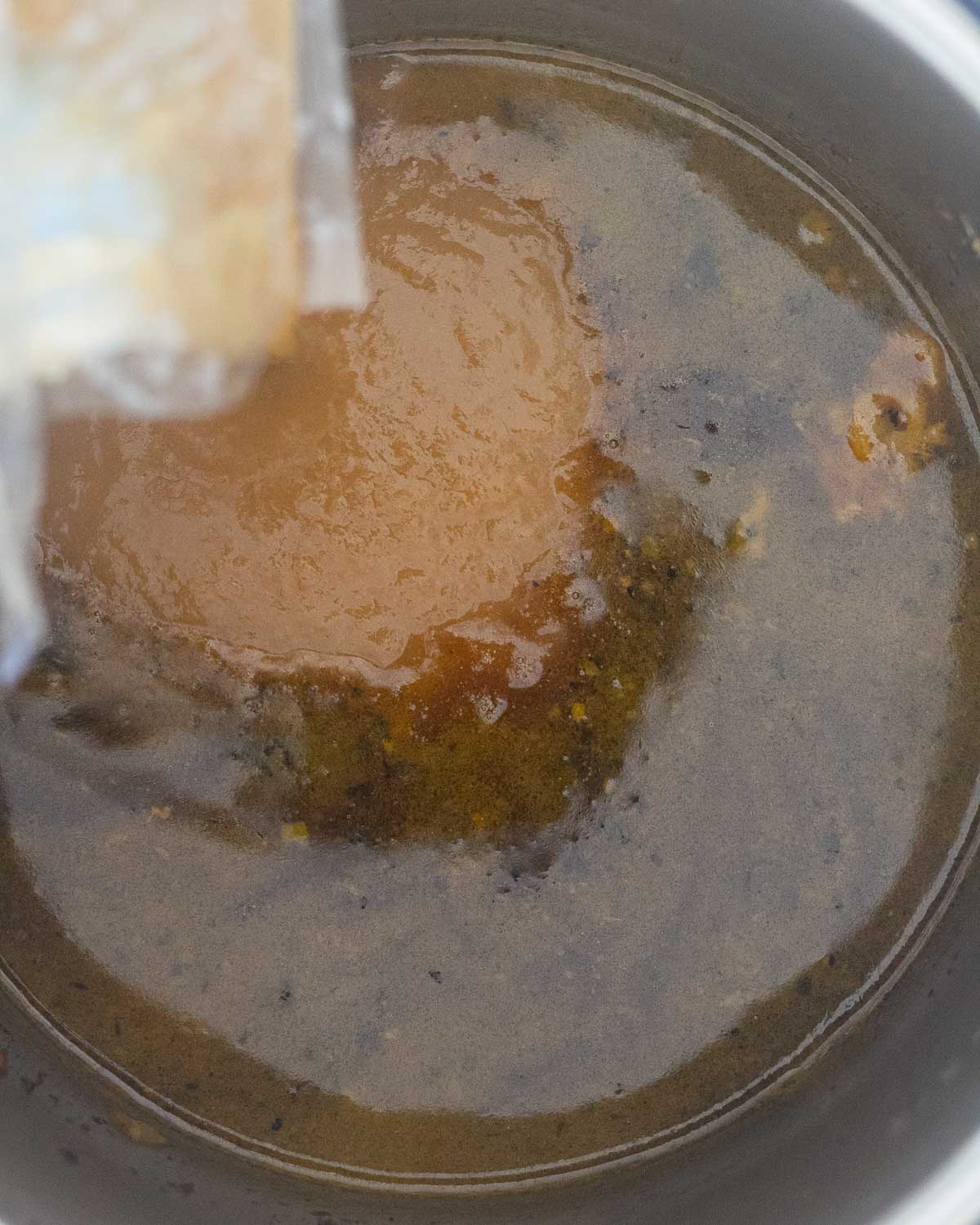 Adding the turkey gravy concentrate to the turkey drippings inside the Instant Pot.