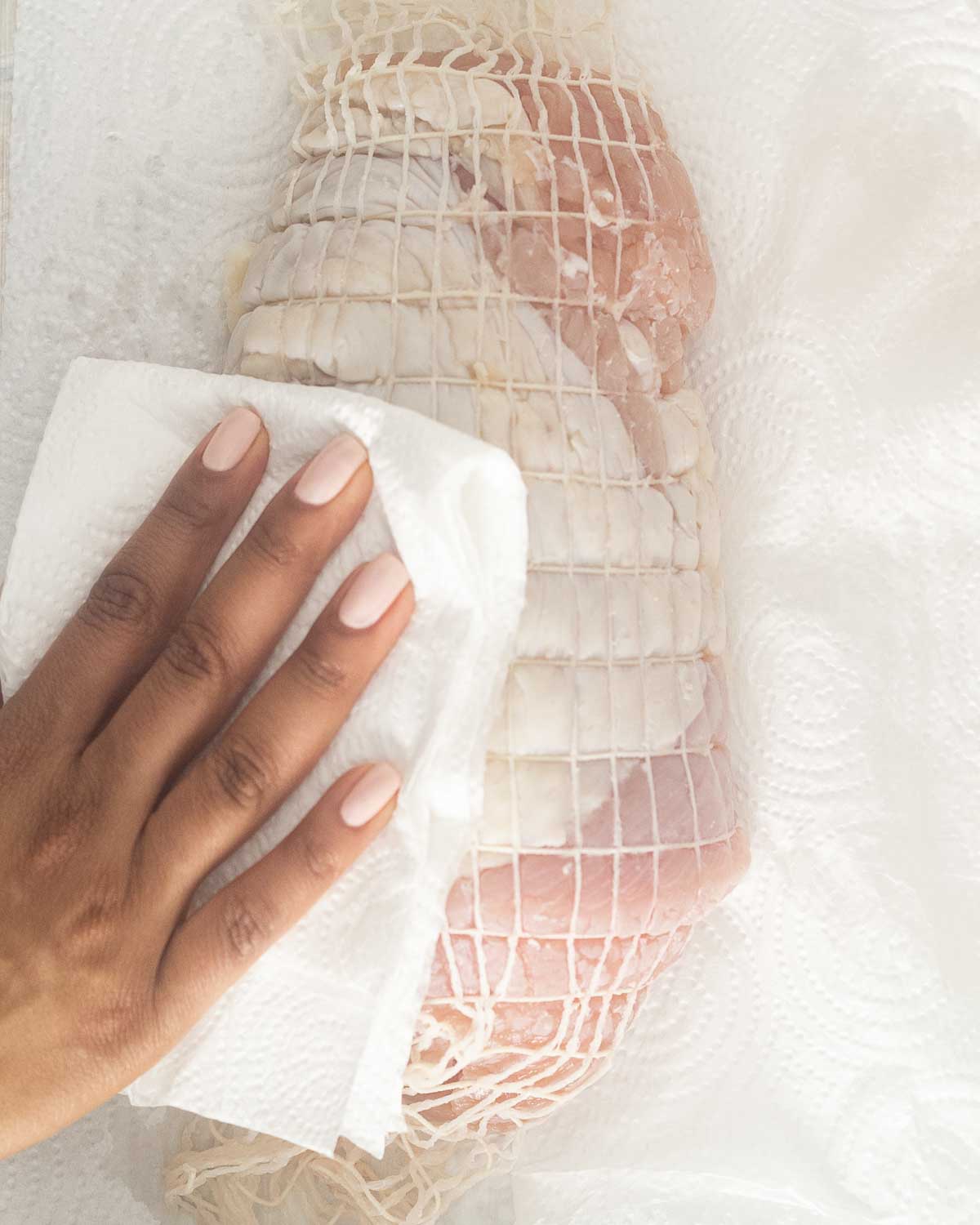 Patting dry a turkey breast with paper towel.