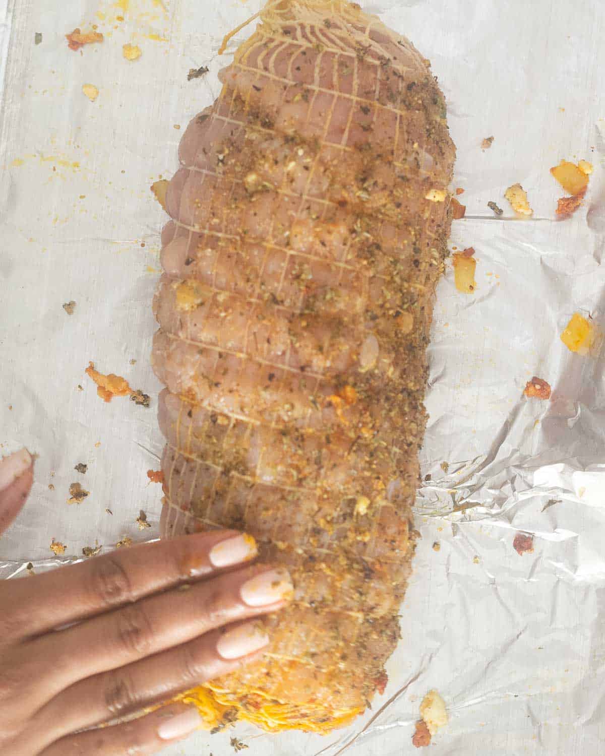 A turkey roll seasoned on a chopping board.