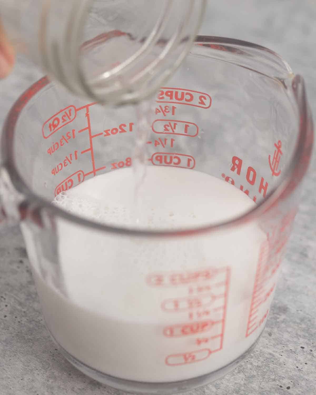 Pouring water into a measuring cup with coconut milk.