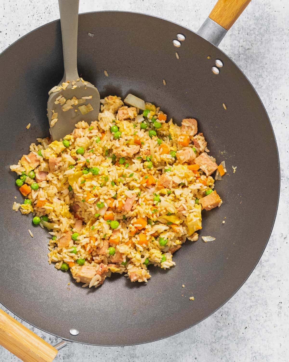 A top view of a wok with cooked ham fried rice.