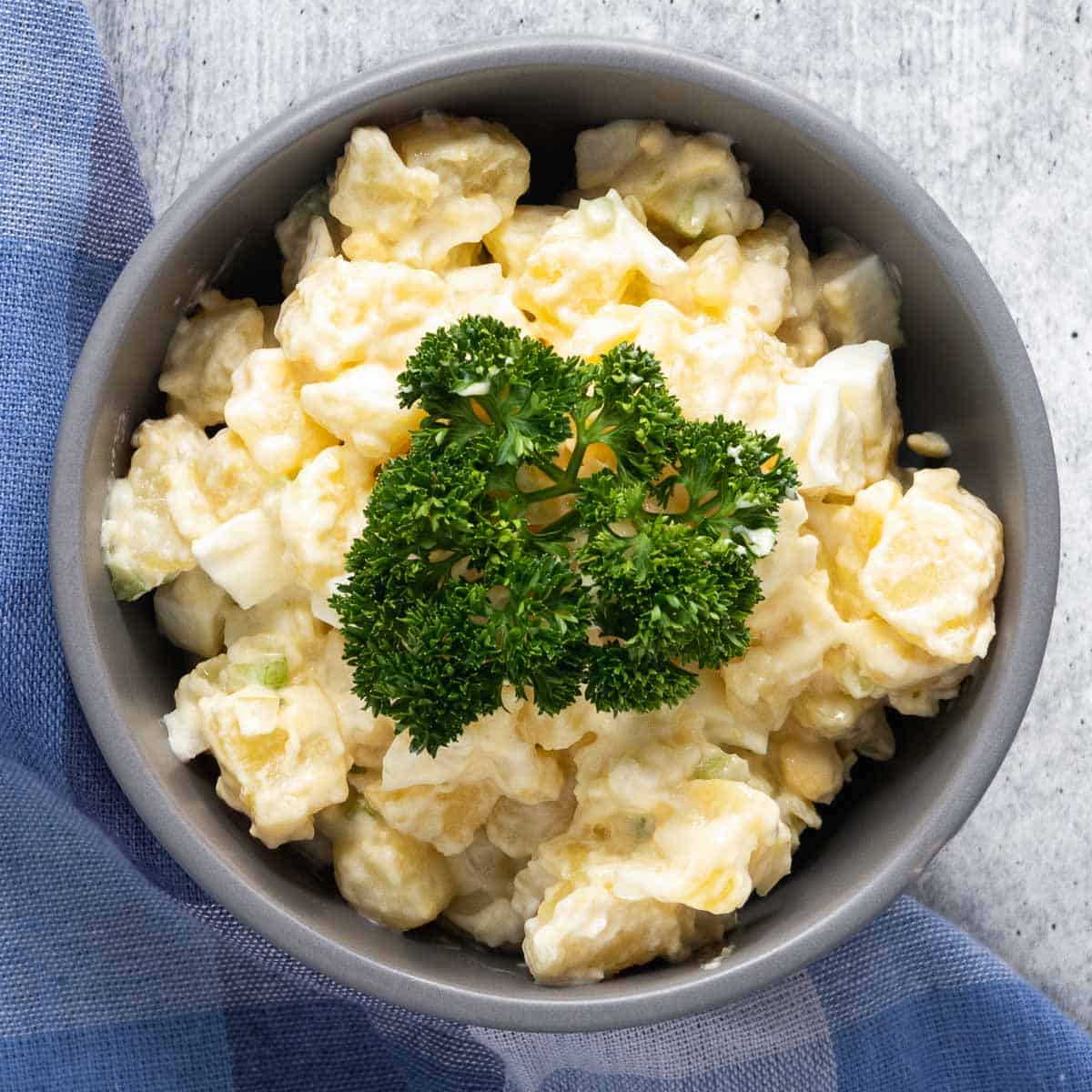 Top view of a bowl with potato salad decorated with curly parsley.