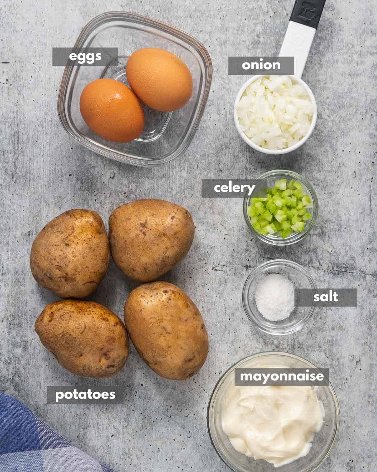 Top view of Ingredients to make potato salad (potatoes, mayonnaise, chopped celery, chopped onions, eggs, and salt).