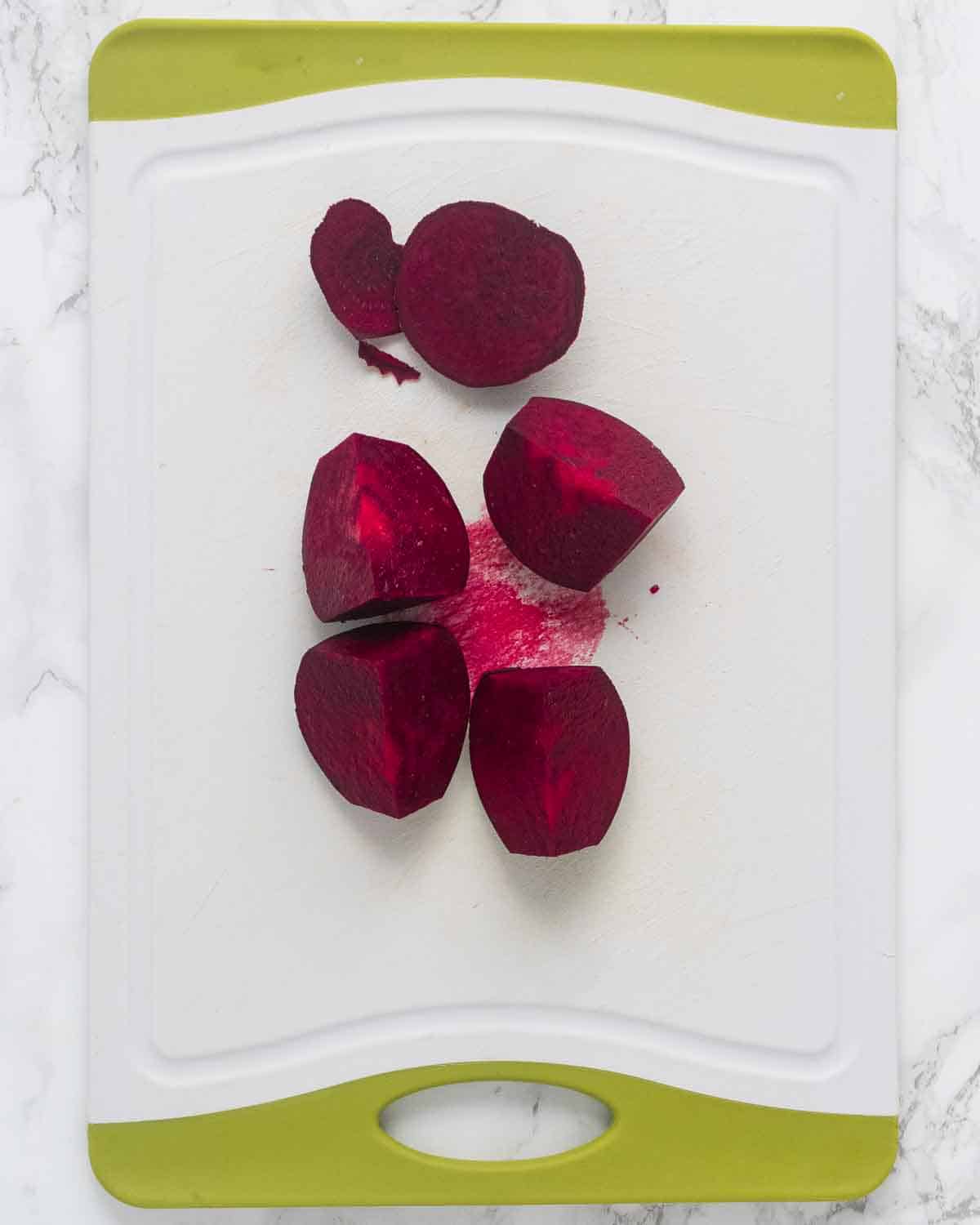 One beet quartered on a chopping board.