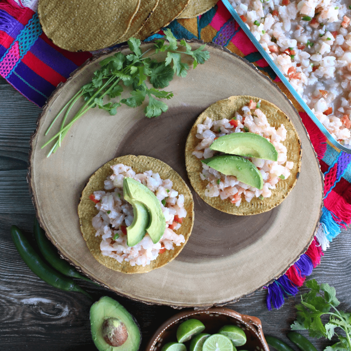 Two tostadas with shrimp ceviche on top and sliced avocado.