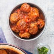 A top-view photo of a bowl with meatballs and tomato sauce.