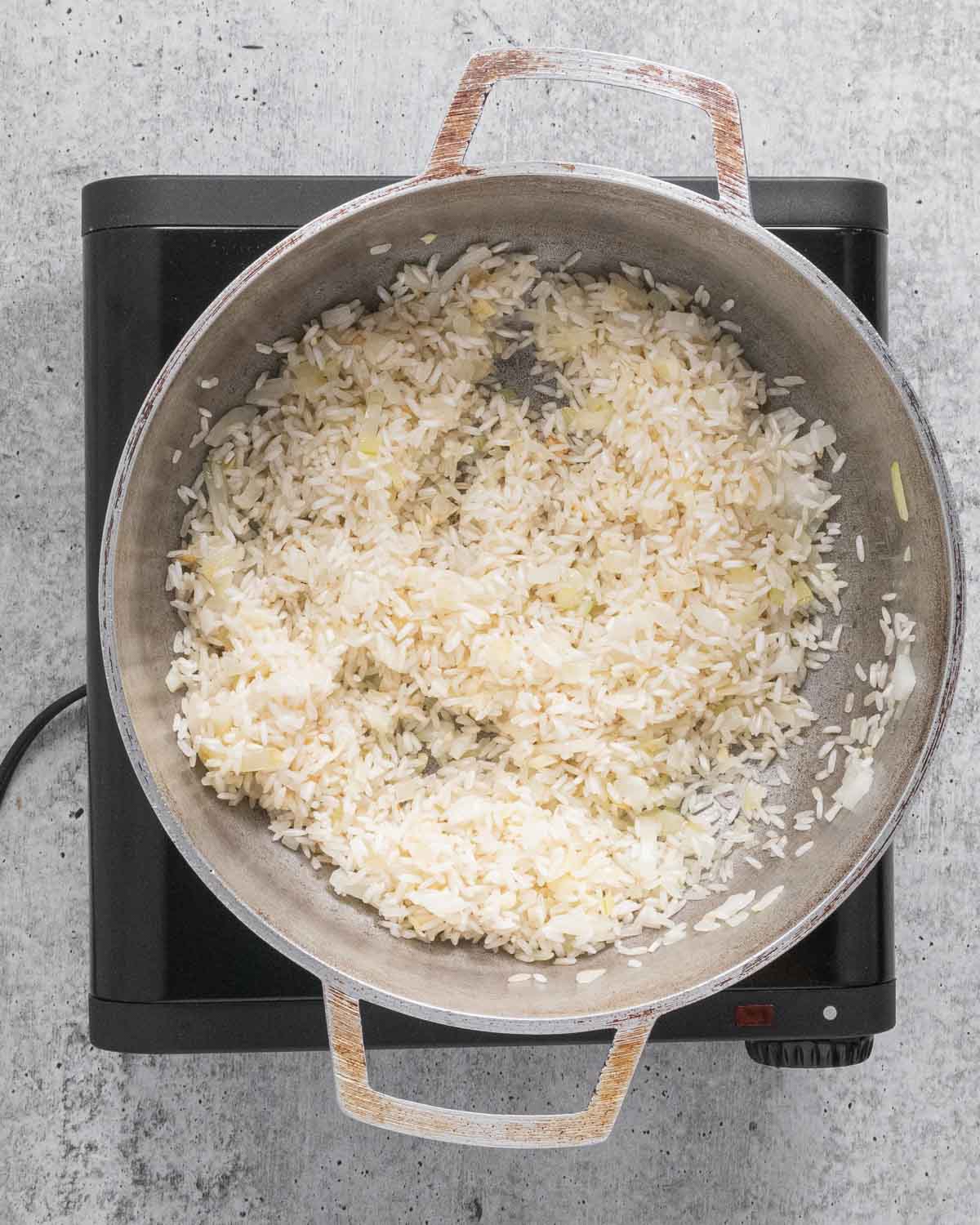 A pot with sautéed onions, garlic, and rice.