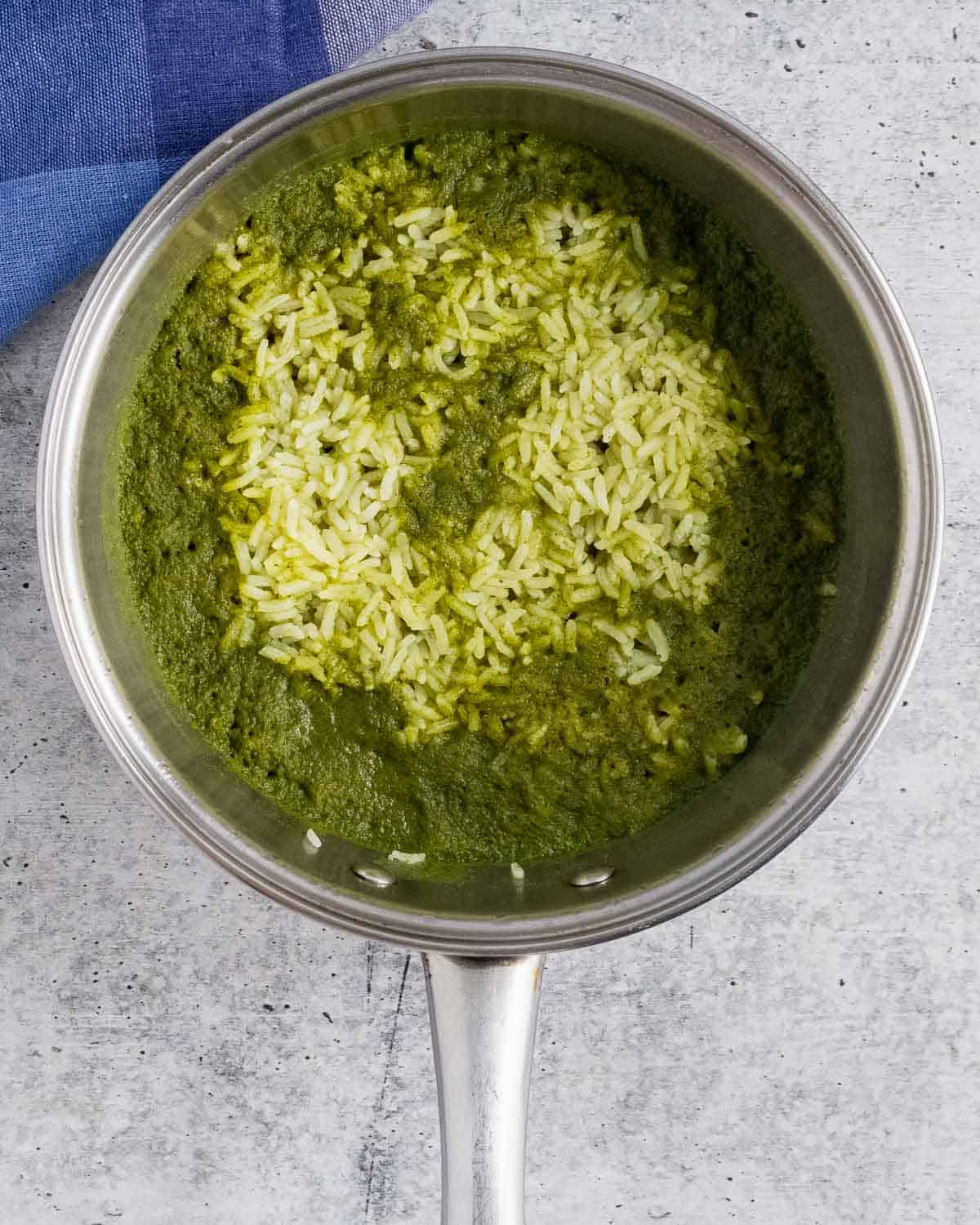 Cooked green rice in a saucepan before fluffing.