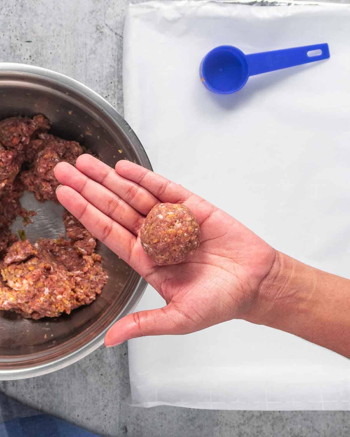 Formed meatballs on a woman's hand.