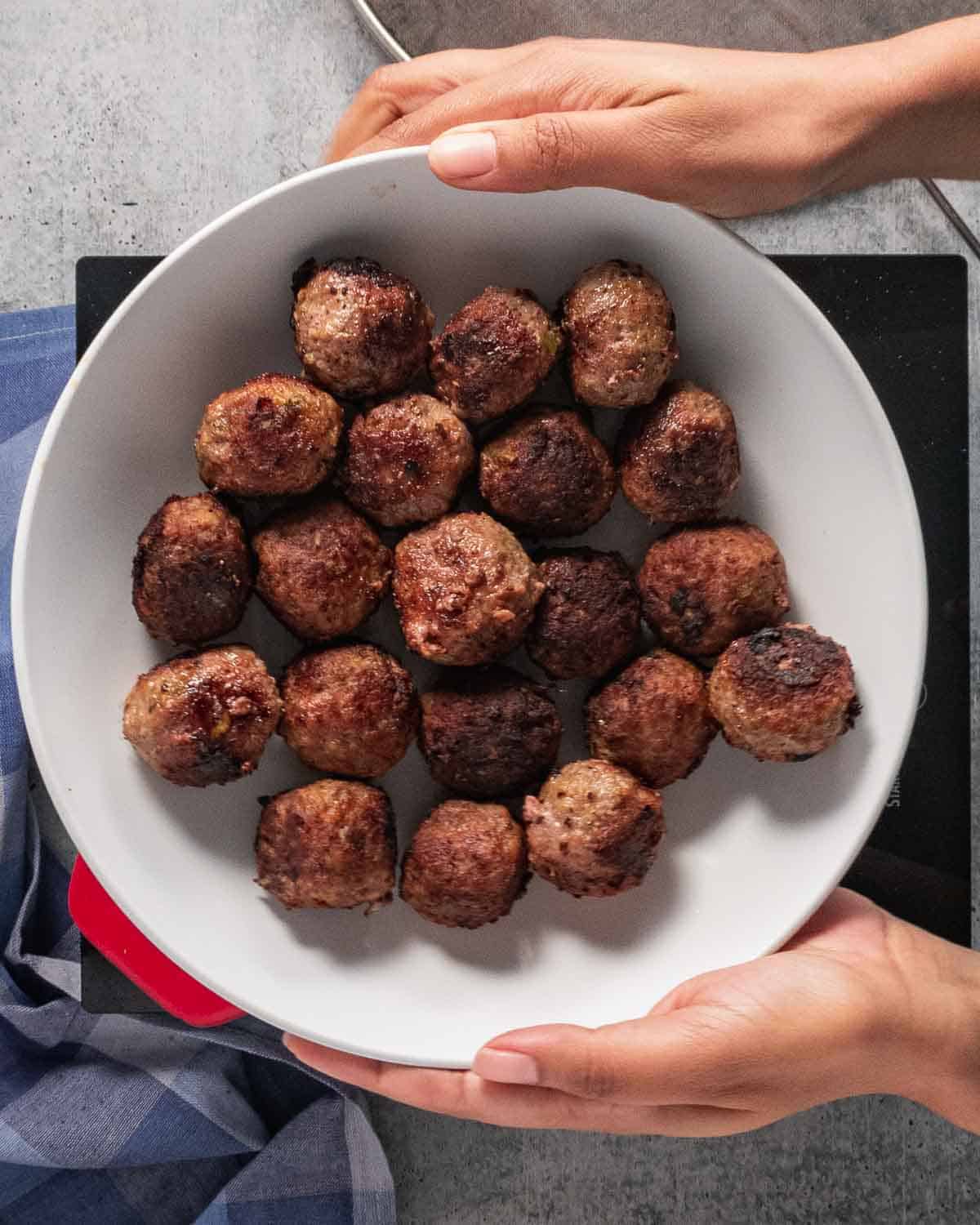 Browned meatballs in a white plate.