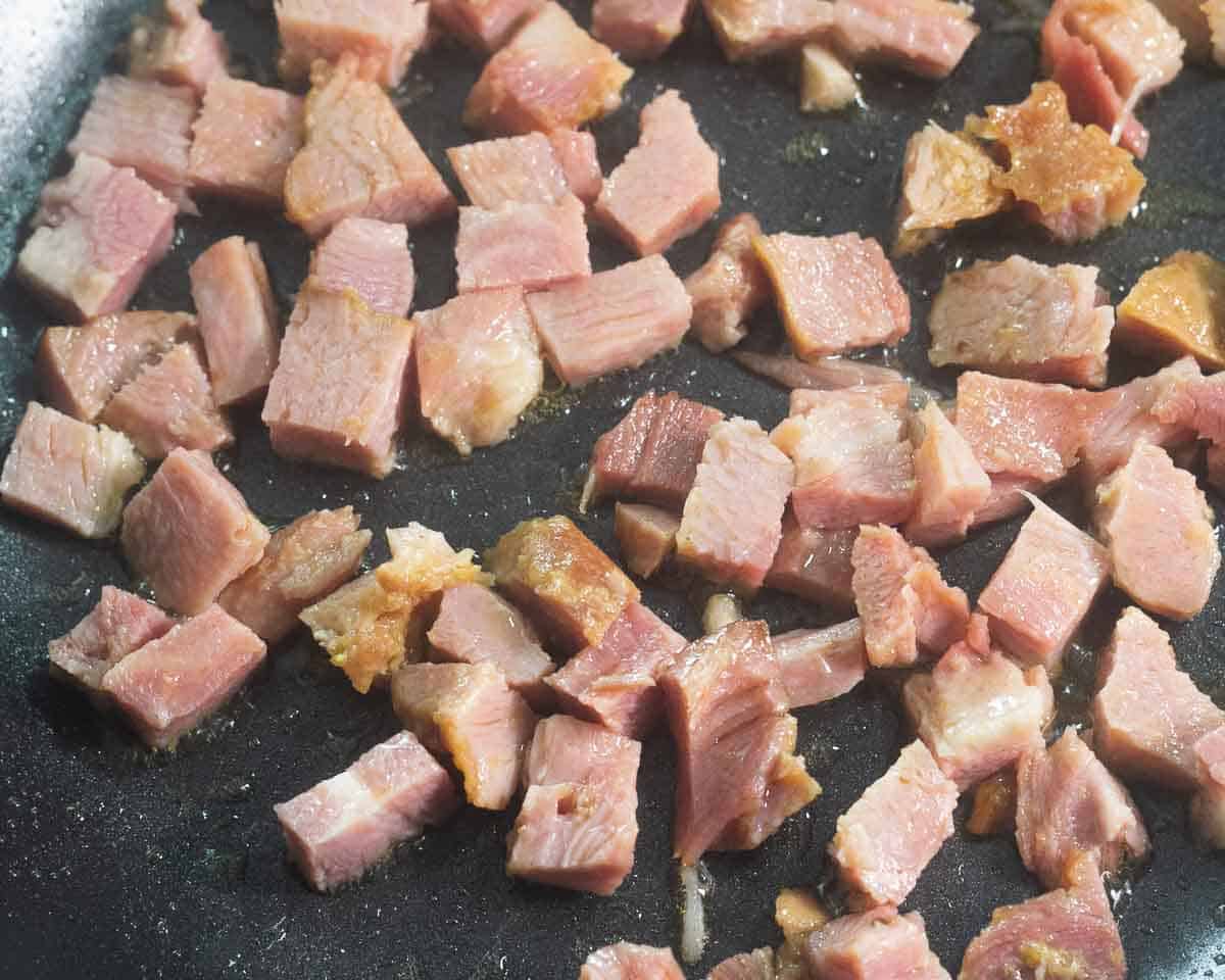 Lightly browned diced ham in a skillet.