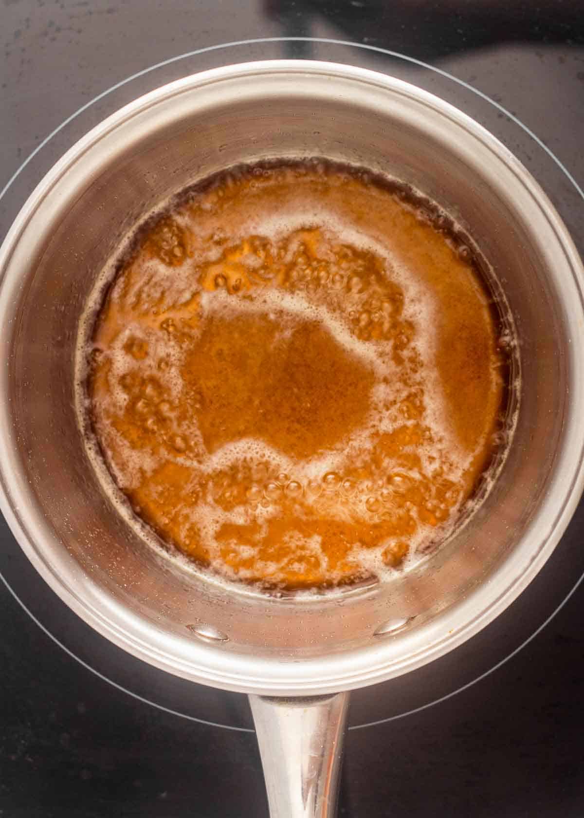 Caramel sauce simmering in a saucepan.