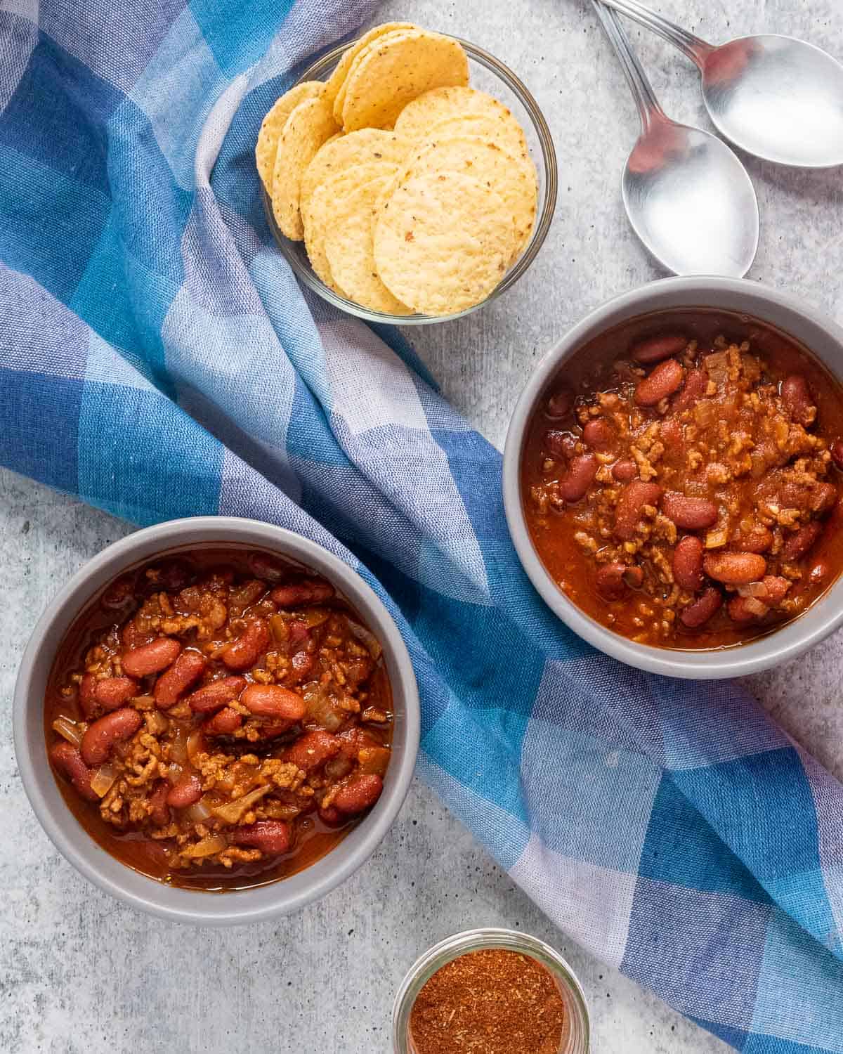 Two bowls of Dutch oven chili and a bowl with nacho chips.