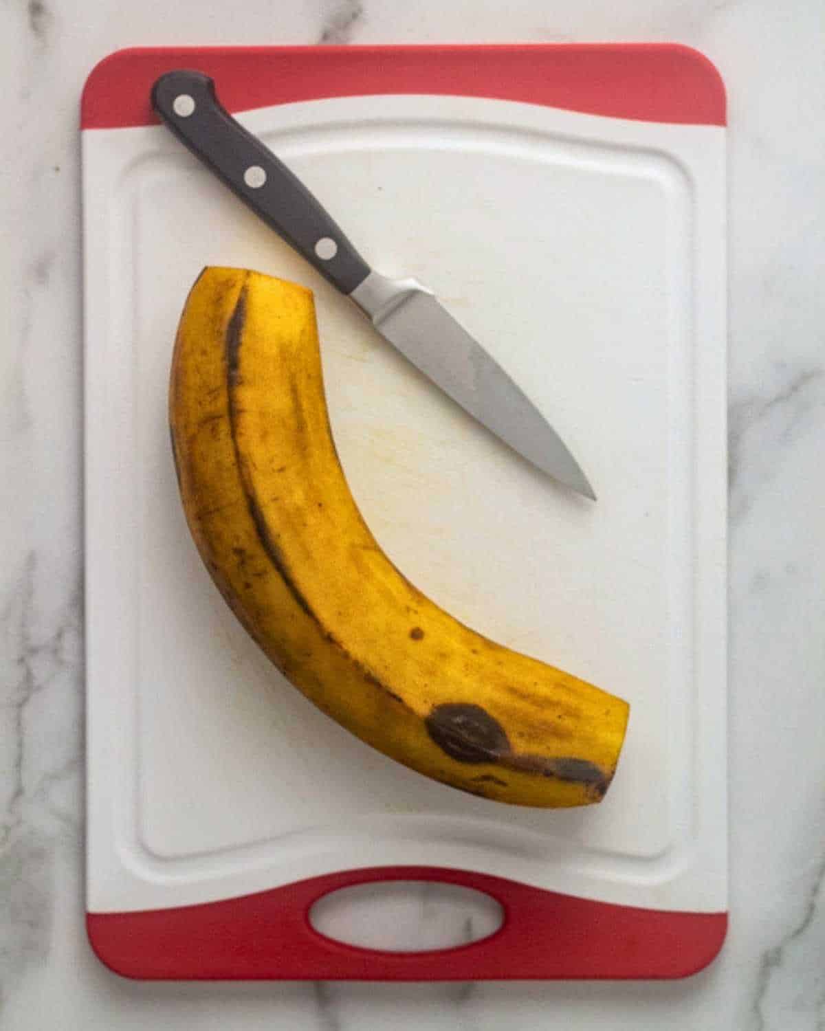 Ripe plantain on a cutting board with ends removed.