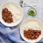 Vista superior de dos platos con arroz blanco y porotos con jamón.